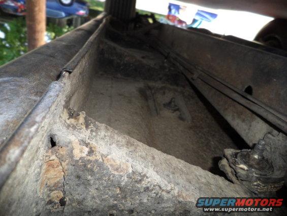rusted car frame section with visible brake lines and mounting hardware