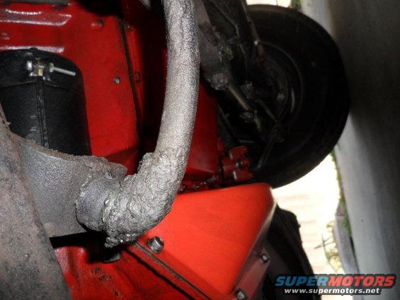 close-up of vehicle undercarriage, showing red painted components, exhaust pipe, and tire