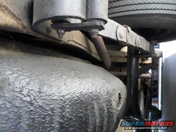 Undercarriage view of a vehicle's fuel tank and suspension. Watermark reads SUPERMOTORS.NET