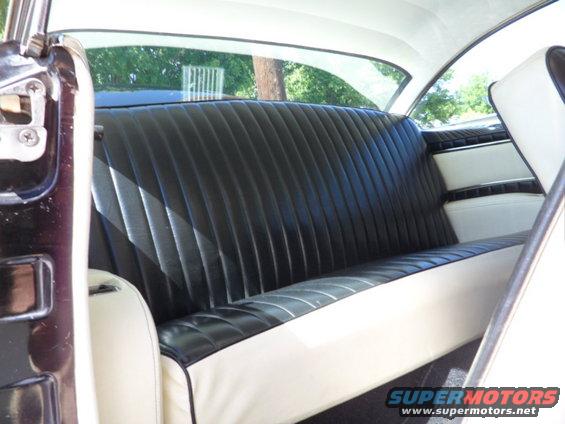 Back seat of a car with black pleated upholstery and white trim