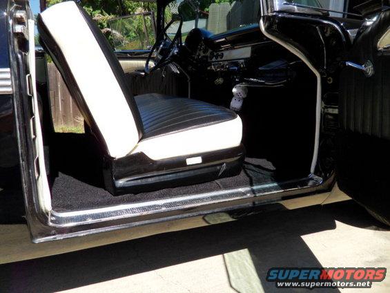 Black and white two-tone interior of a classic car, showing the driver's seat and dashboard