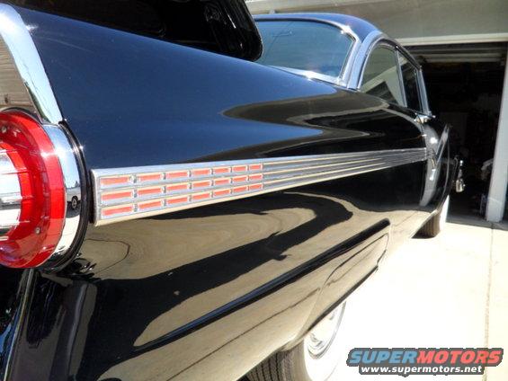 Black 1956 Ford Fairlane rear quarter panel with chrome trim and red taillight