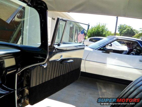 interior of a classic car with door open, showing another car parked next to it