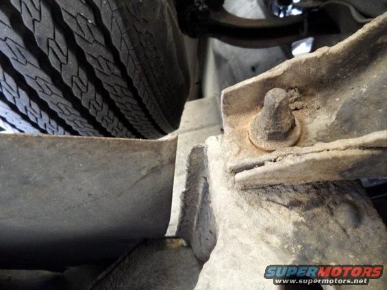 Undercarriage view of a vehicle's tire and rusty metal frame components