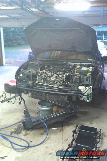 imag0255.jpg Four bolts remain, almost ready to pull. You can see the dented radiator support and fresh timing belt / water pump... one will be replaced, one is replacing the old, leaky pump in the new engine.