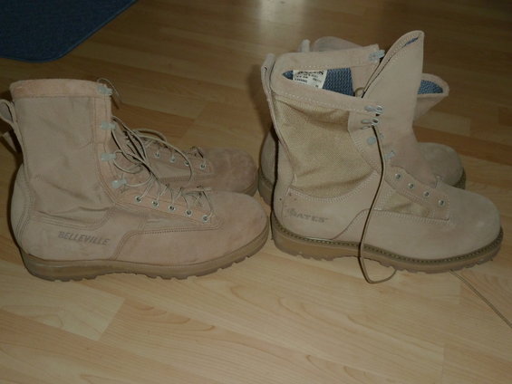 two pairs of tan combat boots, one Belleville and one Bates, on a wooden floor