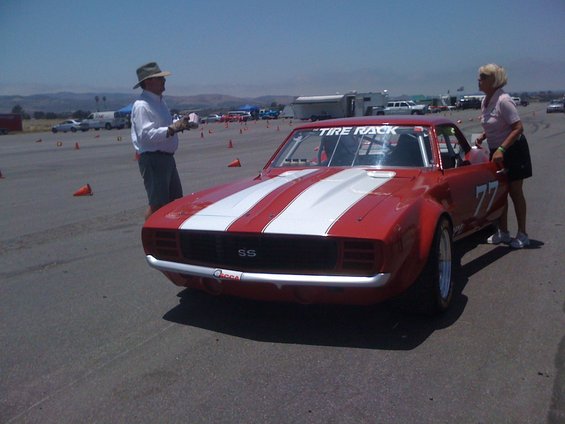 Red 1969 Chevrolet Camaro SS race car with white stripes and number 77 on the door