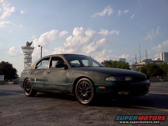 Dark green sedan with aftermarket wheels, 3/4 front view