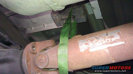 Close-up of a vehicle's driveshaft and U-joint, with a green strap attached