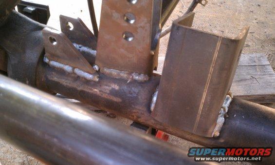 Close-up of welded metal brackets attached to a vehicle's axle tube