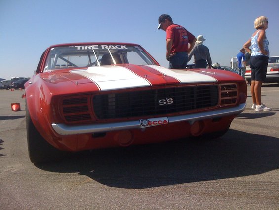 Front view of a red 1969 Camaro SS race car with white stripes and "The Tire Rack" banner