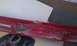 1991 Ford Festiva - A red plastic trim piece with mounting hardware is shown, possibly from a vehicle.
