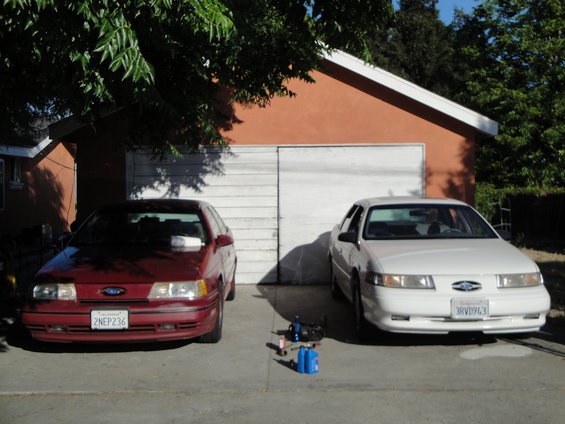 1992 Ford Taurus (red) and 1996 Ford Taurus (white) parked in front of garage