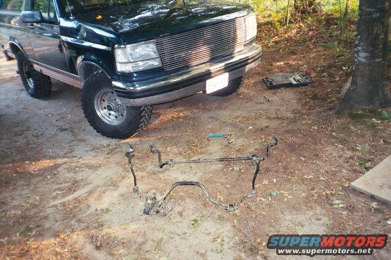 Dark green Ford F-Series truck parked outside with steering components on the ground