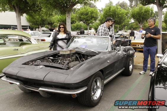 Black 1963 Corvette convertible with engine exposed, parked outdoors