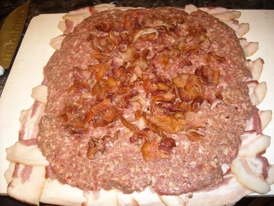 Meatloaf mixture shaped and wrapped with bacon slices, topped with crumbled bacon