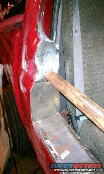 red vehicle body panel with fresh welds and a rusty pipe sticking out