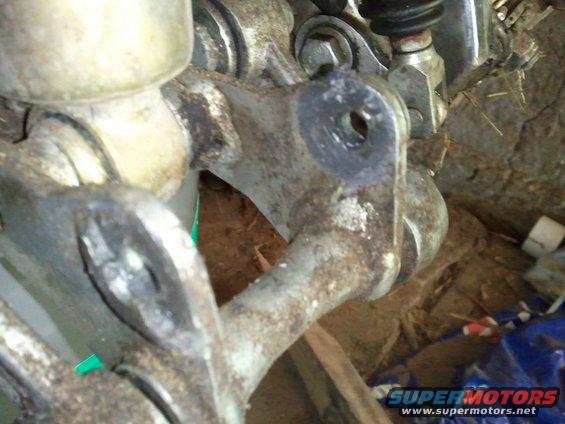 Close-up of a rusty, dirty vehicle suspension component, possibly a control arm or bracket