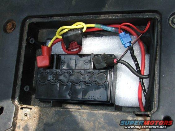 Battery compartment with red and yellow wires connected to a black battery