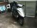 2008 Yamaha Zuma - A black and silver scooter is parked on a concrete patio next to outdoor furniture and a storage shed.