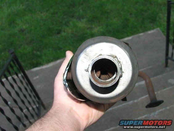 Exhaust pipe held in hand, showing internal baffles. Supermotors.net logo visible