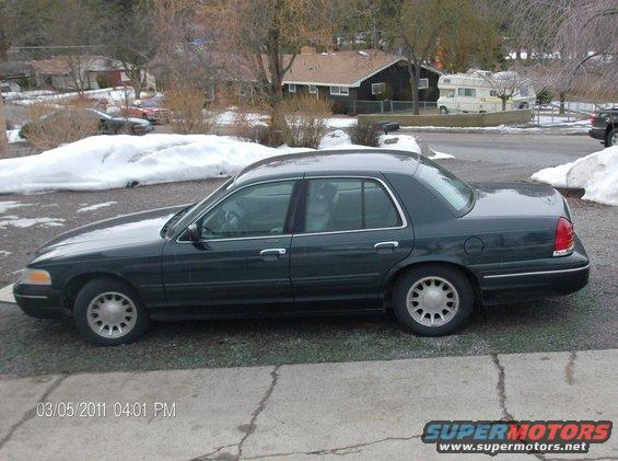 Dark green sedan parked on a concrete driveway with snow in the background