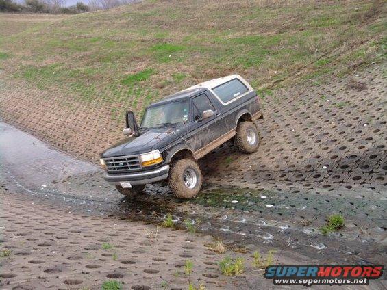 1994 Ford Bronco climbing a wet, textured embankment