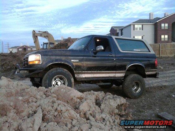 Dark blue 1994 Ford Bronco with lifted suspension on dirt