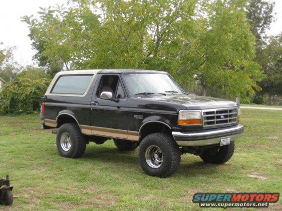 Black 1994 Ford Bronco with tan trim and aftermarket wheels parked on grass