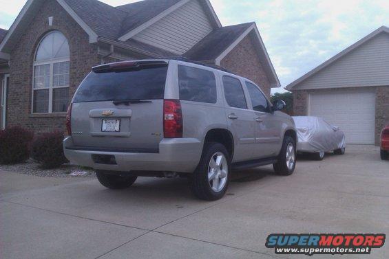 Rear view of a 2007 Chevrolet Tahoe parked in a driveway next to a covered car