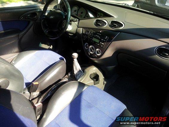 Interior shot of a 2002 Ford Focus, showing the dashboard, steering wheel, seats, and gear shifter