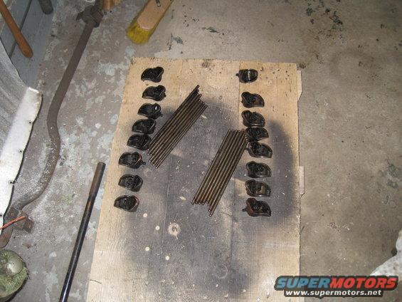 Engine rocker arms and pushrods laid out on a wooden board