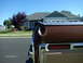 1979 Ford F-150 - The rear corner of a truck is visible, with a toolbox mounted on the bed rail. A house is in the background.