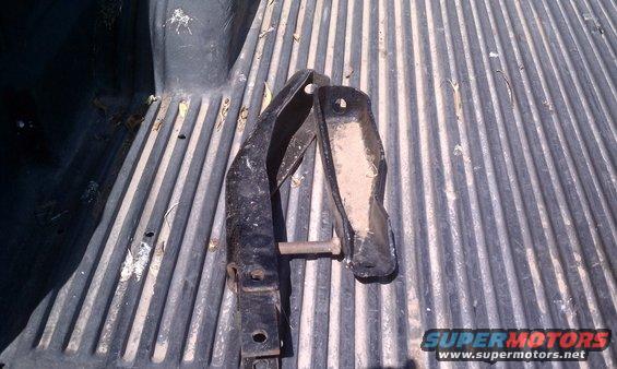 Two metal brackets with a bolt, resting on a ribbed truck bed