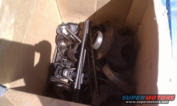 Box of assorted engine parts, including what look like valve springs and pushrods