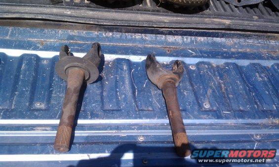 Two driveshaft yokes with splined ends, resting on a blue truck bed