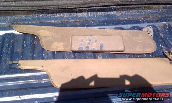 Two tan sun visors, one with a mirror, resting on a blue truck bed