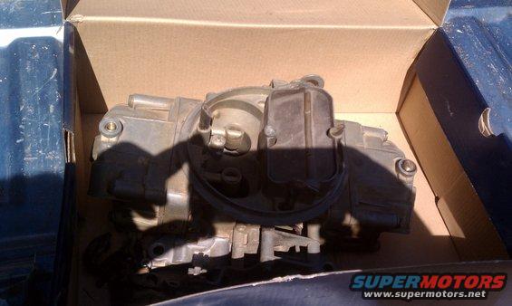 Carburetor sitting in a cardboard box, possibly in the bed of a truck