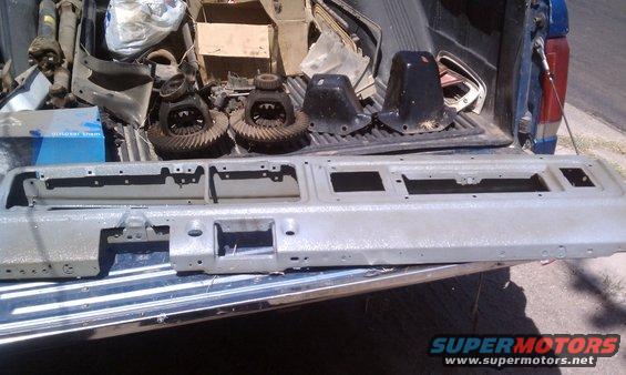 Truck bed loaded with differential gears, metal covers, and a large gray panel