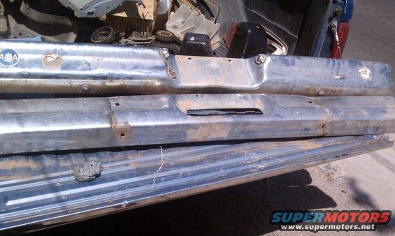 Two chrome bumpers stacked in a truck bed, one with an 'AMA' logo