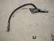 1992 Ford Taurus - A damaged brake hose with a metal fitting on one end and a loop on the other, resting on a concrete surface.