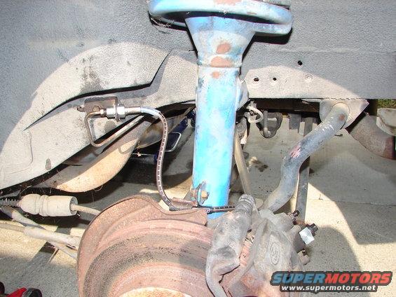 close-up of a car's front brake rotor, caliper, and suspension strut