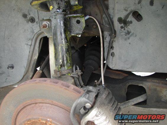 Close-up of a car's front brake rotor, caliper, and suspension components