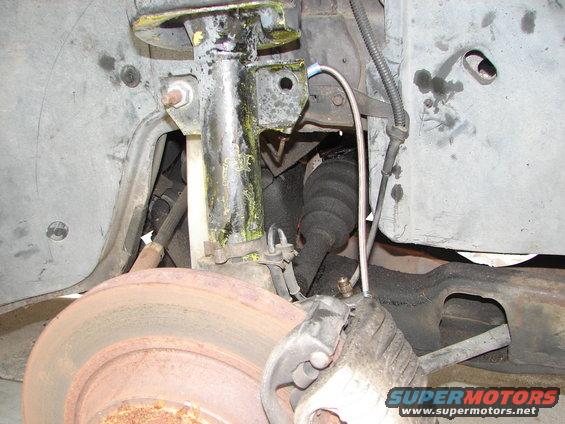 Close-up of a car's front suspension, showing the shock absorber, brake rotor, and CV axle boot