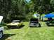 1975 Ford Ranchero - Two vehicles are parked on a grassy field under trees, with people gathered nearby.