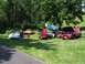 1975 Ford Ranchero - Several classic cars are displayed on a grassy field under trees, with tents set up in the background.