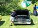 1975 Ford Ranchero - A man poses with a green 1975 Ford Ranchero at an outdoor car show. The vehicle's hood is open, revealing the engine.