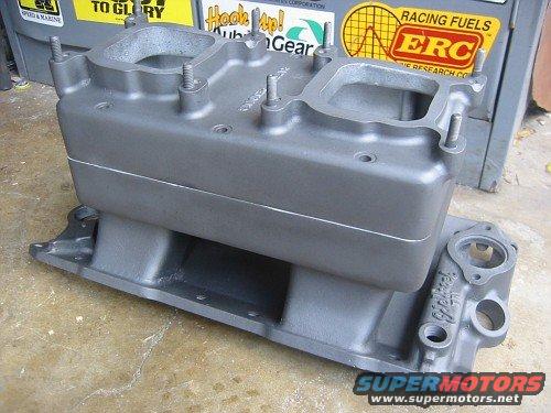 Gray metal intake manifold with two carburetor mounting holes on top. Text on the side reads 'Edelbrock'