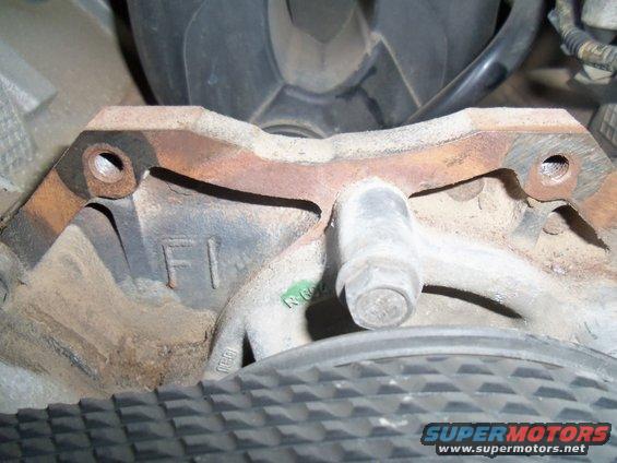 Close-up of a rusty metal engine component with 'F1' cast into it and a bolt