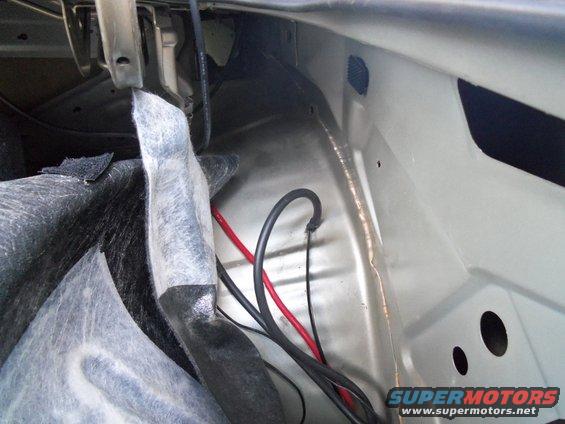 Inside of a car trunk showing wiring and insulation. Supermotors.net logo visible